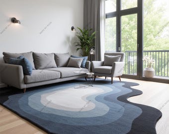 May include: A blue and white abstract rug with a wavy design. The rug is in a living room with a gray sofa and a gray armchair.