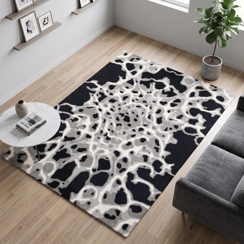Puede incluir: Una alfombra rectangular con un patr&oacute;n abstracto de alto contraste en negro, blanco y varios tonos de gris. El dise&ntilde;o consiste en formas org&aacute;nicas y fluidas que se asemejan a un mapa topogr&aacute;fico o a una estructura celular sobre la superficie.