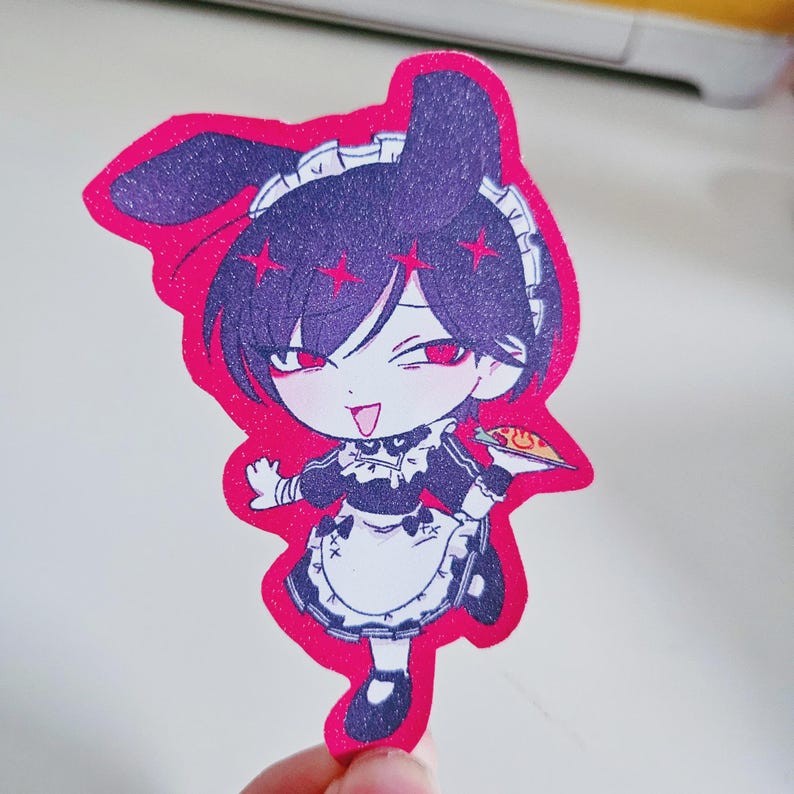 May include: A die-cut sticker featuring an anime-style character in a maid outfit. The character has dark purple hair, red eyes, and is holding a plate of food. The sticker has a pink glittery border.