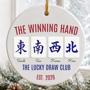 May include: A round white ceramic ornament with a gold hanging string. It features the red text THE WINNING HAND above four mahjong tiles with blue Chinese characters. Below are the names Sarah, Sue, Karen, Kim, THE LUCKY DRAW CLUB, and EST. 2026.