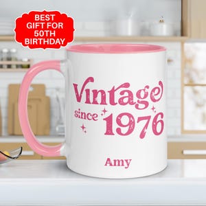 May include: White ceramic mug with a pink interior and handle. The mug features the text "Vintage since 1976" in pink script, with the name "Amy" below. A red tag in the upper left corner reads "Best Gift for 50th Birthday."