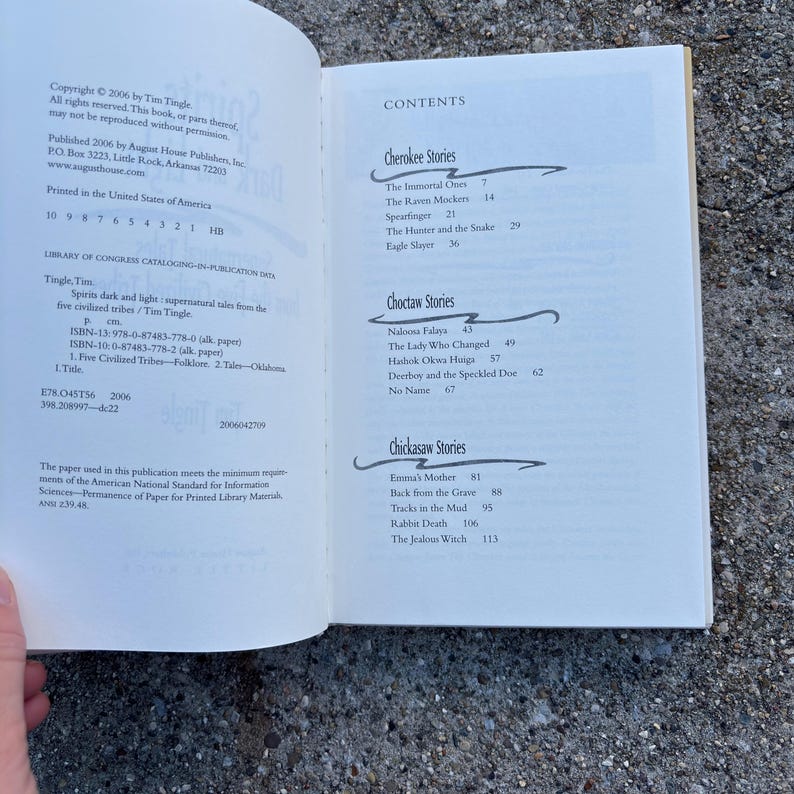 May include: Open book displaying the contents page of "Spirits Dark and Light," featuring Cherokee, Choctaw, and Chickasaw stories. The book's copyright is 2006. The page includes a list of stories with page numbers.