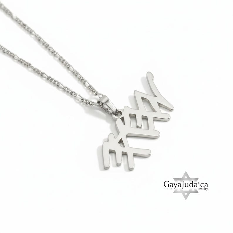 May include: A silver-colored necklace with a pendant featuring Hebrew script. The pendant is connected to a delicate chain. The necklace is displayed on a white background. The logo "Gaya Judaica jewelry" is in the bottom right corner.