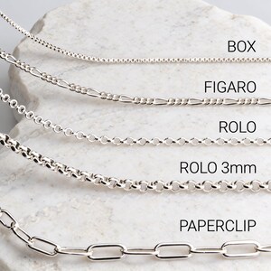 Sterling silver chain comparison on white marble: box, figaro, rolo, 3mm rolo and paperclip necklace chains with labels