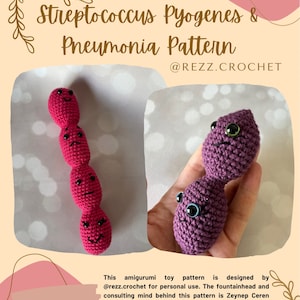May include: Two crocheted amigurumi toys representing Streptococcus pyogenes and pneumonia bacteria. The Streptococcus pyogenes is pink and has a chain of four connected spheres. The pneumonia bacteria is purple and has two connected spheres. Both toys have facial expressions.