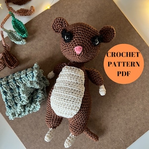 May include: Crochet pattern PDF for a brown and white amigurumi animal with black eyes and a pink nose. The animal is lying on a brown surface.