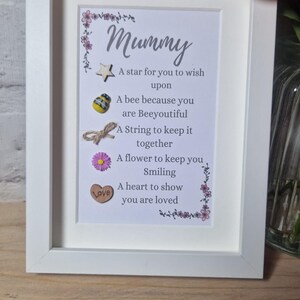Op de afbeelding: Een wit frame met een gedicht erin dat luidt: "Mummy A star for you to wish upon A bee because you are Beeyoutiful A String to keep it together A flower to keep you Smiling A heart to show you are loved". Het gedicht is versierd met een ster, een bij, een touwtje, een bloem en een hart.
