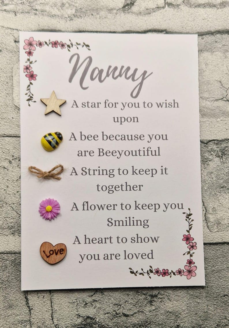 Op de afbeelding: Een witte kaart met het woord "Nanny" in cursief. De kaart heeft een gedicht erop dat zegt: "Een ster om een wens te doen, Een bij omdat je prachtig bent, Een touwtje om het bij elkaar te houden, Een bloem om je te laten glimlachen, Een hart om te laten zien dat je geliefd bent". De kaart heeft een ster, een bij, een touwtje, een bloem en een hart.