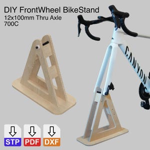 Può includere: Supporto per bici DIY FrontWheel in legno chiaro, progettato per sostenere la ruota anteriore di una bicicletta. Il testo "DIY FrontWheel BikeStand 12x100mm Thru Axle 700C" è visibile. Il supporto è mostrato con una bicicletta bianca.