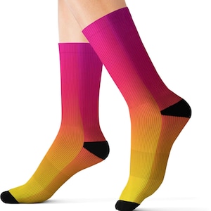 May include: A pair of gradient-colored socks. The socks transition from a vibrant pink at the top to a warm yellow at the toes. The heels and toes are black. The socks are ribbed.