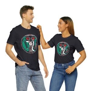 May include: Two people wearing black t-shirts with a graphic of a clock face with gears and a green background. The clock face has red and white accents.
