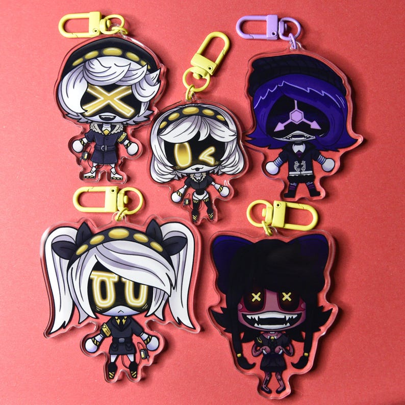 May include: A collection of acrylic keychains featuring anime-style characters. Each keychain showcases a unique character design with vibrant colors, including black, white, yellow, and purple. The keychains have yellow or purple clasps.