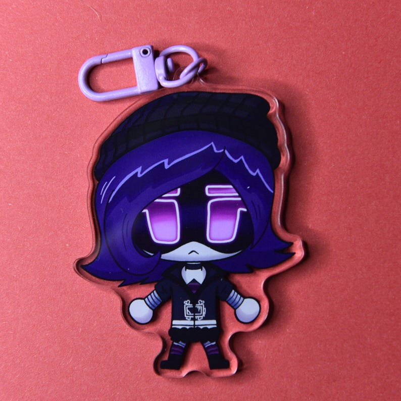 May include: A purple and black cartoon character keychain with a purple clasp. The character has purple hair, a black hat, and a black outfit. The character's eyes are purple rectangles. The keychain is made of clear acrylic.
