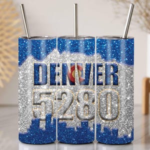 May include: Three stainless steel tumblers with a silver glitter finish and a blue and white design. The tumblers feature the text "DENVER 5280" and a graphic of the Colorado state flag.