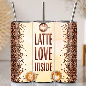 Peut inclure: Un gobelet isotherme en acier inoxydable avec un motif sur le thème du café. Le gobelet présente un fond beige clair avec les mots "LATTE LOVE INSIDE" en marron. Des grains de café bordent les côtés. Comprend une paille argentée.