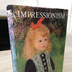 May include: A vintage hardcover book titled "Impressionism" with a colorful illustration of a young girl with blonde hair wearing a blue dress with white buttons. The book cover features a green background with red flowers.
