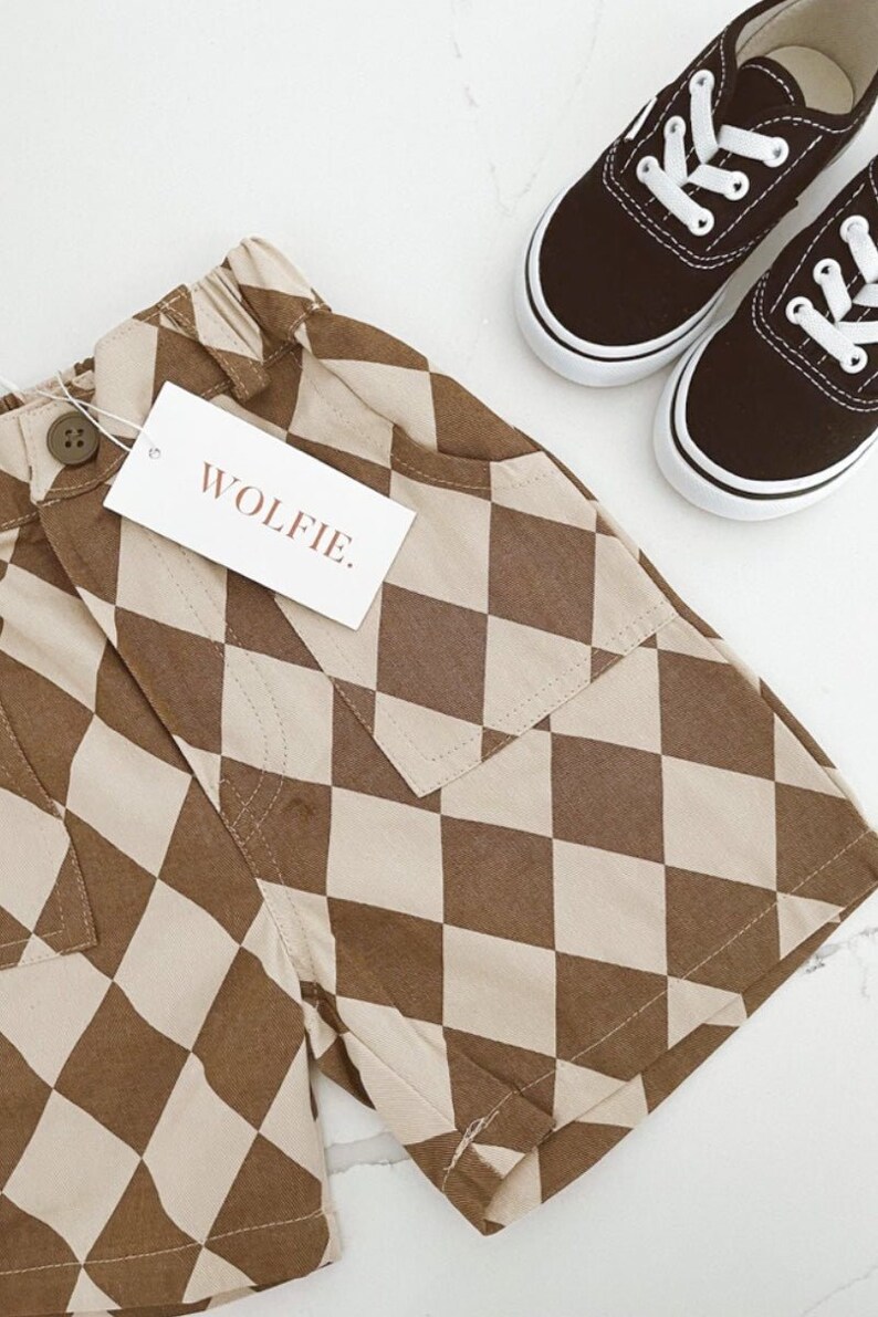 Puede incluir: Shorts de cuadros marrones y beige con un solo bolsillo y una etiqueta que dice "WOLFIE."
