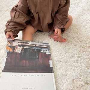 May include: A brown book with the title "This Is Home" and the subtitle "The Art of Simple Living" by Natalie Walton.