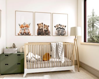 May include: A nursery scene featuring three framed animal prints: foxes, bears, and raccoons. A wooden crib with a white base is in the foreground, along with a green dresser and a floor lamp. The room has a neutral color palette.