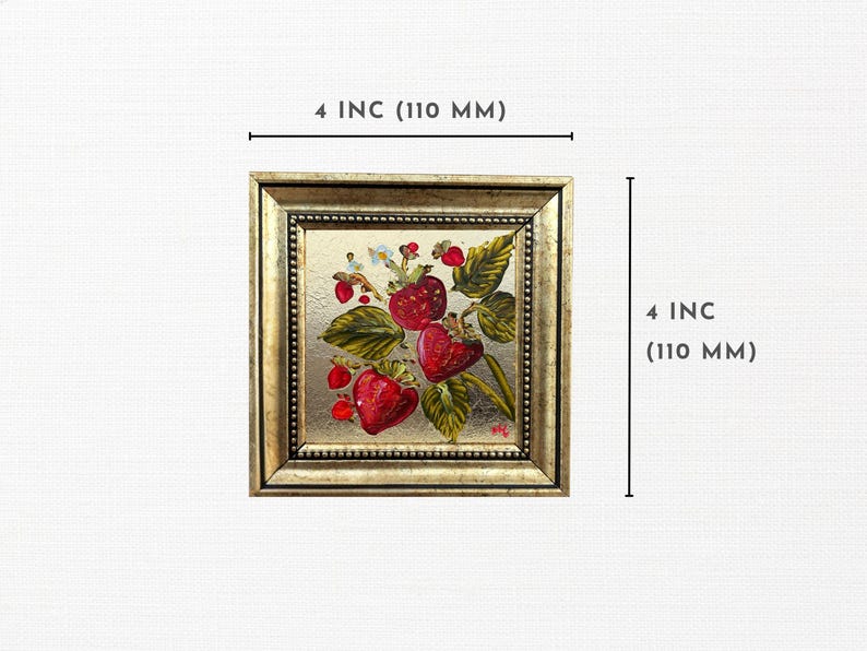 Op de afbeelding: Vierkant ingelijst kunstwerk met aardbeien. De goudkleurige lijst omringt een schilderij van rijpe rode aardbeien met groene bladeren en witte bloemen. Het kunstwerk meet 10 cm per zijde.