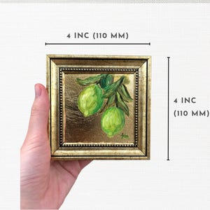 May include: A small, framed painting of a green lime branch with two limes. The frame is gold with a beaded border. The painting is 4 inches by 4 inches.