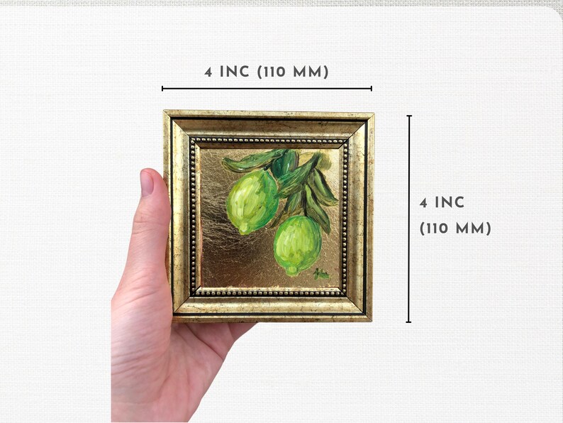 May include: A small, framed painting of a green lime branch with two limes. The frame is gold with a beaded border. The painting is 4 inches by 4 inches.