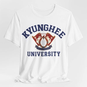 May include: White t-shirt with a blue and red graphic of the Kyunghee University logo. The logo features a crest with two women holding scrolls and the text "Kyunghee University".