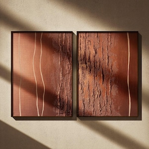 Può includere: Due opere d'arte astratte incorniciate. L'opera presenta una superficie strutturata marrone-rossastra con linee bianche verticali su un pannello e una texture ruvida simile alla corteccia sull'altro. Le cornici sono marrone scuro e lo sfondo è una parete beige chiaro.