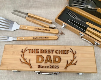 May include: A bamboo barbecue tool set with stainless steel utensils. The set includes a spatula, fork, tongs, and a knife, all with bamboo handles. The wooden box is engraved with "THE BEST CHEF DAD Since 2025" and antler designs.