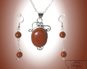 May include: A silver necklace with a brown stone pendant and matching earrings. The necklace and earrings have small brown beads along the chain.