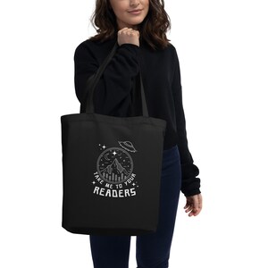 May include: Black tote bag with a white graphic design of a mountain, moon, stars, and a UFO. The text on the bag reads "Take me to your readers".