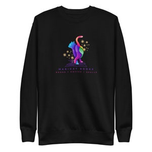 May include: Black sweatshirt with a colorful cat illustration and the text "MAGICAT BOOKS BOOKS | COFFEE | SPELLS" printed on the front.