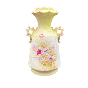 May include: A vintage ceramic vase with a pale yellow and green gradient. The vase features a floral design of daisies and roses in pink, white, and yellow. It has two ornate handles and a ruffled top.