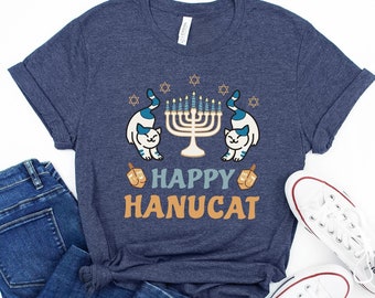 May include: A navy blue t-shirt with a white cat on each side of a menorah with the text "Happy Hanucat".