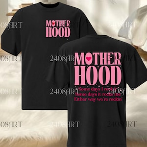 Può includere: T-shirt nere con la scritta "MOTHERHOOD" in rosa, con un cuore rosa. La parte posteriore della maglietta riporta la scritta "Some days I rock it, some days it rocks me, either way we're rockin'" in rosa.
