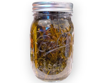 May include: A clear glass jar with a silver lid filled with dried herbs and a yellow liquid. The jar has the word "Ball" and "Mason" printed on it.