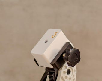 May include: A white and black adjustable mounting bracket with a green circular base, featuring a central pivot mechanism with black adjustment knobs. Two additional white plastic components, two small metal screws, and a black washer are included.