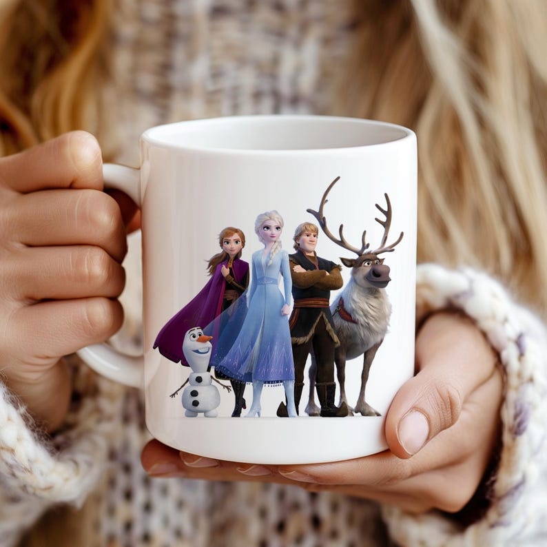 May include: White ceramic mug with a colorful image of the characters from the movie Frozen. The characters include Elsa, Anna, Kristoff, and Olaf. The reindeer Sven is also in the image.