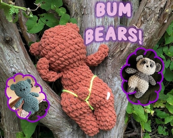 Op de afbeelding: Drie gehaakte teddyberen, een bruine, een grijze en een zwart-witte. De bruine beer draagt ​​een groene en witte stringbikini. De tekst "Bum Bears!" staat in roze letters op een boomstam achter de beren.