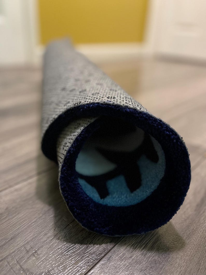 May include: A rolled up rug with a blue and white pattern. The rug has a dark blue border.