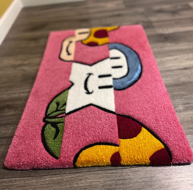 Puede incluir: Una alfombra rosa con una estrella blanca, hojas verdes y tres setas con detalles amarillos y rojos.