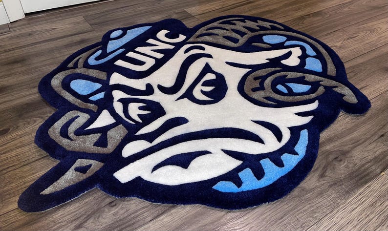 May include: A blue and white rug with a cartoon ram's head and the text "UNC" on it.