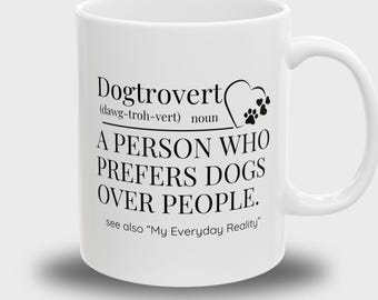 May include: White ceramic mug with a black graphic that reads "Dogtrovert (dawg-troh-vert) noun A PERSON WHO PREFERS DOGS OVER PEOPLE. see also "My Everyday Reality""