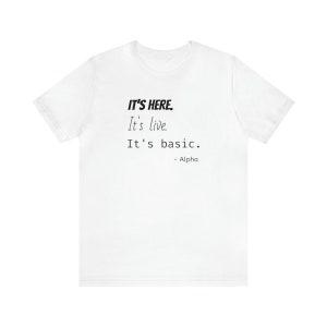May include: White t-shirt with black text that reads "IT'S HERE. It's live. It's basic. - Alpha"