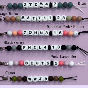 May include: Five colorful silicone bead keychains with different names and numbers. The keychains are made of various colors, including blue, green, pink, black, and grey. Each keychain has a silver metal clasp.