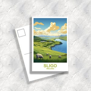 以下が含まれることがあります： アイルランド、スライゴの風景を描いた絵葉書。緑の丘、青い川、雲の多い空が描かれています。羊が前景で草を食べています。「SLIGO」と「IRELAND」の文字がカードの下部に印刷されています。