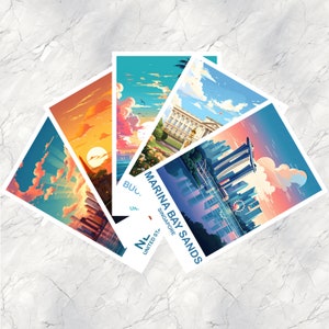 May include: Five colorful postcard designs featuring different cityscapes. The postcards are arranged in a fan shape with the top postcard showing a cityscape with a large building with a curved roof. The text on the postcard reads "Marina Bay Sands Singapore".