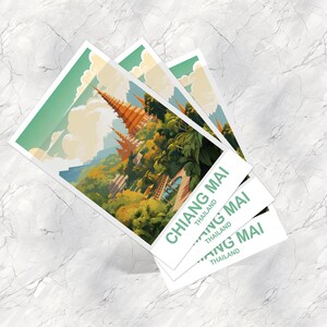 May include: Three square postcards featuring a colorful illustration of a temple complex in Chiang Mai, Thailand. The postcards have a white border and the text "CHIANG MAI" and "THAILAND" in green. The background is a marble surface.
