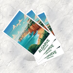 Op de afbeelding: Drie gestapelde ansichtkaarten met een kleurrijke illustratie van een strandsc&egrave;ne met kliffen en blauw water. De tekst op de ansichtkaarten luidt "ALGARVE PORTUGAL".