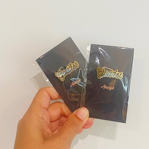 May include: Two gold-colored pins with the text "God 1st" and "Always" on black card stock.